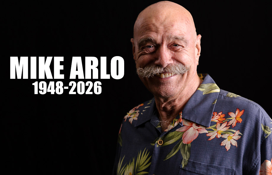 Memorial portrait of Mike Arlo (1948–2026) with a smiling man in a floral aloha shirt against a black background.